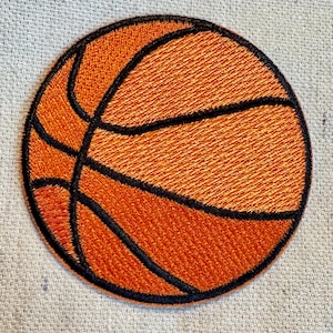 Puede incluir: Parche bordado de baloncesto. El parche redondo presenta un fondo naranja con líneas negras, que reproducen el diseño de un balón de baloncesto. Para ropa o accesorios.