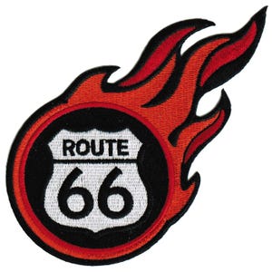 May include: A red, white, and black embroidered patch with a Route 66 sign inside a circle with flames coming out of the top. The sign says "Route 66" in black text.