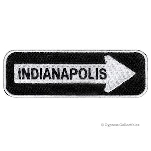 May include: Black and white embroidered patch with a white arrow pointing to the right and the text "INDIANAPOLIS" in white.