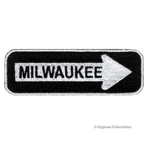 May include: Black and white embroidered patch with a white arrow pointing to the right and the word "MILWAUKEE" in white letters.