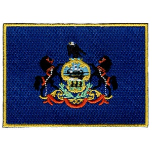 May include: Embroidered patch featuring the state seal of Pennsylvania. The seal depicts a blue and gold shield with a ship, a green tree, and two horses. The horses are flanked by two eagles, and the entire design is surrounded by a red and gold ribbon.