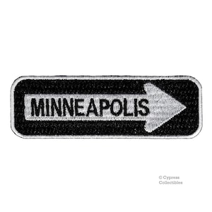 May include: Black and white embroidered patch with a white arrow pointing to the right and the text "MINNEAPOLIS" in white.