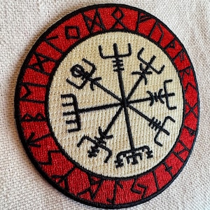 May include: A red and white embroidered patch with a compass design and the text "Vegvisir" around the edge.