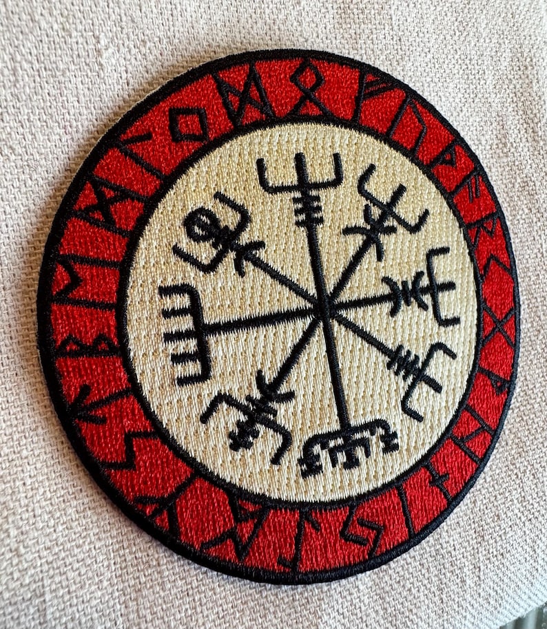 May include: A red and white embroidered patch with a compass design and the text "Vegvisir" around the edge.