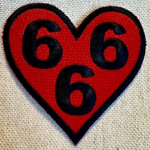 May include: Red felt heart-shaped patch with three black embroidered numbers '666'.
