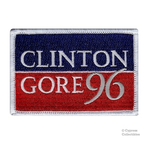 May include: A blue and red embroidered patch with white stitching. The patch features the text "CLINTON GORE 96" in white.
