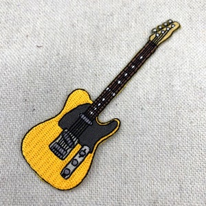 Op de afbeelding: Een gele elektrische gitaar met een zwarte pickguard en een bruine hals. De gitaar heeft een enkele cutaway en een traditioneel ontwerp.