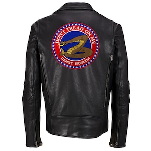 Può includere: Giacca di pelle nera con una toppa ricamata in rosso, bianco e blu che dice "Don't Tread On Me" con un serpente a sonagli avvolto e le parole "Liberty" e "Freedom".