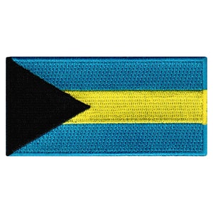 May include: A rectangular embroidered patch featuring the flag of the Bahamas. The flag is blue with a black triangle in the upper left corner and a yellow horizontal stripe in the center.