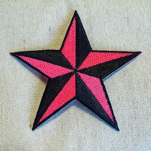 Op de afbeelding: Een zwart en roze nautische ster-patch. De ster is geborduurd met een roze en zwart ontwerp.