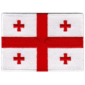 May include: A white patch with a red cross in the center and four smaller red crosses in the corners. The patch is made of a woven fabric.