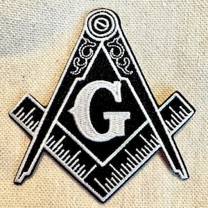 Puede incluir: Parche bordado en blanco y negro con una brújula y un cuadrado con una gran letra "G" blanca en el centro.