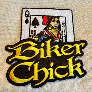 May include: A black and yellow embroidered patch with the text "Biker Chick" and a Queen of Spades playing card image.