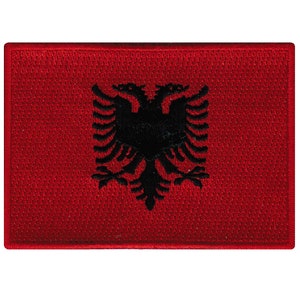 May include: A red embroidered patch with a black double-headed eagle, the national symbol of Albania.