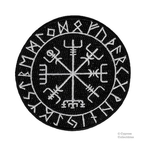 May include: Black and white embroidered patch with a compass design and runes around the edge. The compass has a central star with four points and eight spokes. The runes are in a circle around the compass and are in a white font.