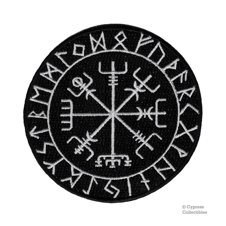 May include: Black and white embroidered patch with a compass design and runes around the edge. The compass has a central star with four points and eight spokes. The runes are in a circle around the compass and are in a white font.