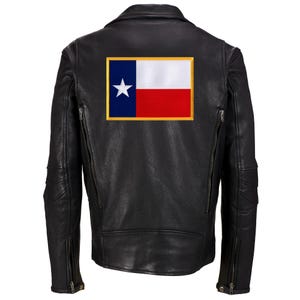 May include: Black leather motorcycle jacket with a Texas flag patch on the back. The jacket features a classic design with a notched collar, zippered pockets, and a tailored fit. The Texas flag patch is rectangular with a blue vertical stripe, white star, white horizontal stripe, and red horizontal stripe.