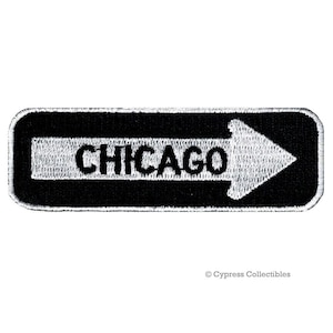 May include: Black and white embroidered patch with a white arrow pointing right and the word "CHICAGO" in black letters.