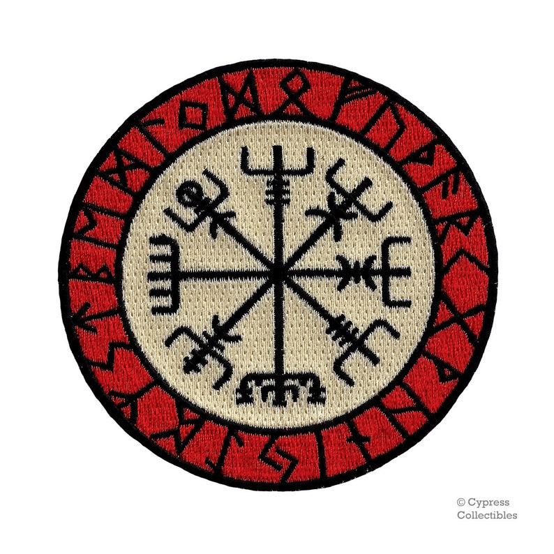 May include: A red and white embroidered patch with a black compass design and runes around the edge. The compass has eight points and is surrounded by a circle of runes.