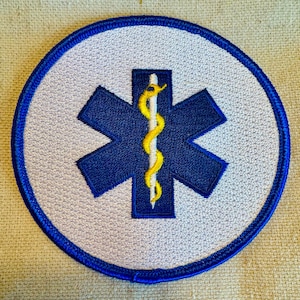 May include: A white embroidered patch with a blue star of life and a yellow caduceus.