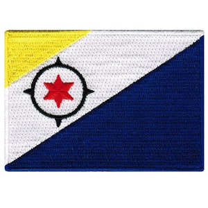 May include: Embroidered patch featuring the flag of Bonaire. The design includes a yellow triangle in the upper left, a white triangle, and a blue triangle. A red six-pointed star is centered within a black compass rose.