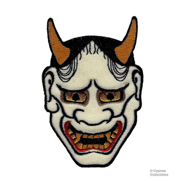 May include: A white embroidered Japanese demon mask with red and gold details. The mask has horns, a wide mouth, and large eyes.