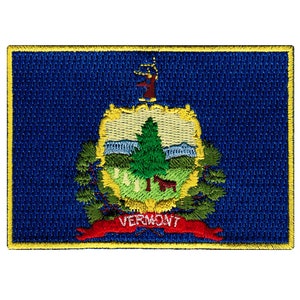 May include: Embroidered patch of the Vermont state flag. The flag is blue with a green pine tree and a yellow background. The words "VERMONT" are written in red on a red ribbon.