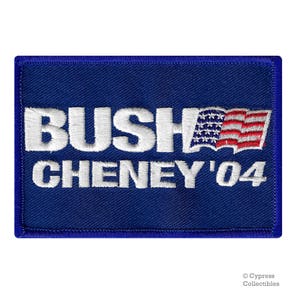 May include: A blue embroidered patch with white text that reads "Bush Cheney '04" and a small American flag.