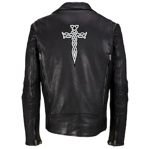 Könnte beinhalten: Schwarze Lederjacke im klassischen Biker-Stil. Verfügt über ein weißes keltisches Kreuz-Design auf dem Rücken. Enthält einen Reverskragen, Reißverschlusstaschen und ein symmetrisches Design. Ein stilvolles Oberbekleidungsstück.