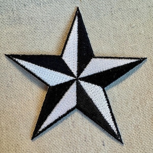 May include: A black and white nautical star patch with a five-pointed star design. The star is made of fabric and has a white outline.