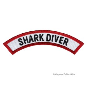 Op de afbeelding: Rode en witte geborduurde patch met de tekst "SHARK DIVER" in zwarte letters.