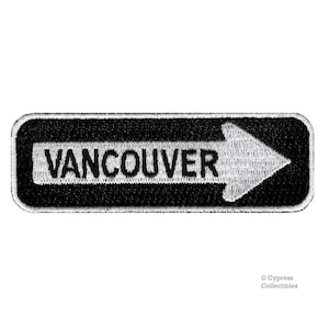 May include: Black and white embroidered patch with a white arrow pointing right and the word "VANCOUVER" in white letters.