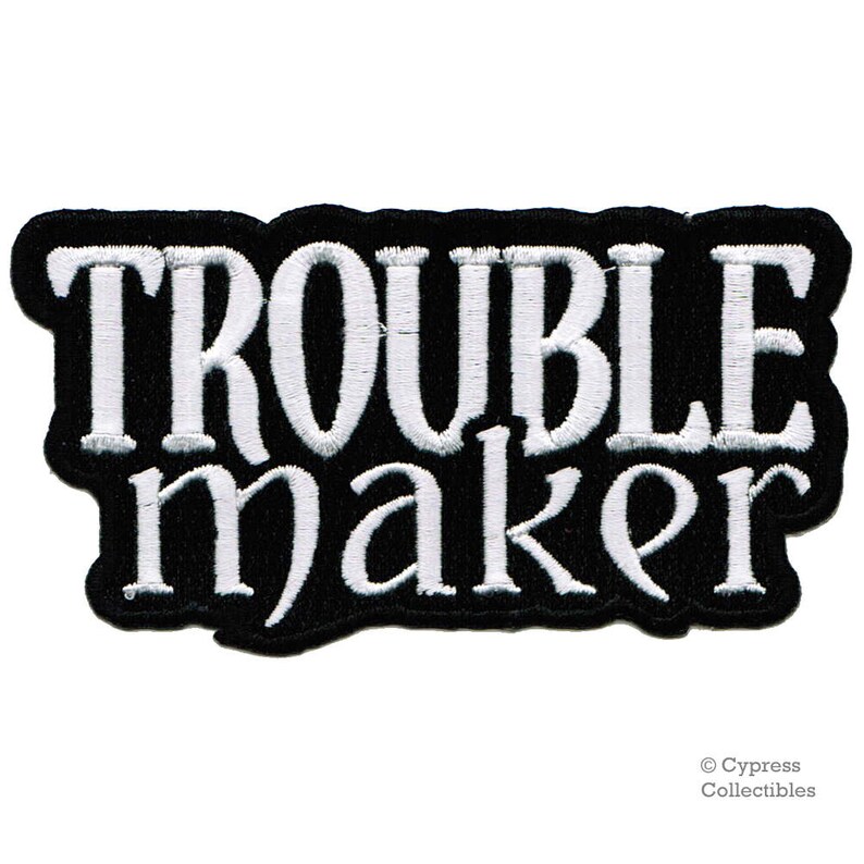 May include: Black and white embroidered patch with the text "Troublemaker" in a bold, stylised font.