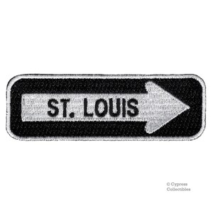 May include: Black and white embroidered patch with a white arrow pointing to the right and the text "ST. LOUIS" in black.