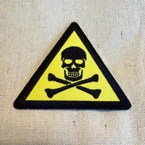 May include: Yellow triangle warning sign with a black skull and crossbones.