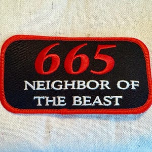 May include: A black and red embroidered patch with the number 665 in red and the text "Neighbor of the Beast" in white.