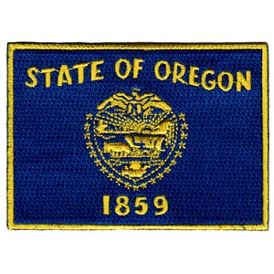 Puede incluir: Un parche bordado azul y dorado con el texto "STATE OF OREGON" y el año "1859".