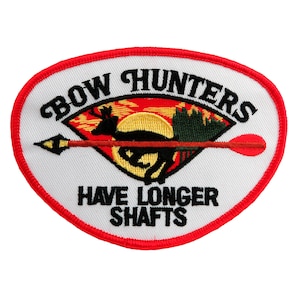 Può includere: Toppa ovale bianca ricamata con bordo rosso. La toppa presenta una silhouette nera di un cervo con una freccia rossa e verde che lo attraversa. Il testo "BOW HUNTERS HAVE LONGER SHAFTS" è ricamato in nero.