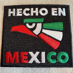 Puede incluir: Parche negro bordado con un diseño de águila rojo, blanco y verde. El texto "HECHO EN MEXICO" está bordado en blanco en el parche.