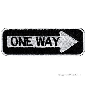 May include: Black and white embroidered patch with the words "ONE WAY" and a white arrow pointing to the right.