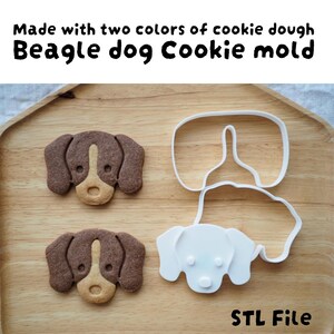 May include: A wooden tray displays two beagle dog cookies made with two colors of dough, next to a white plastic cookie cutter. The cookies are brown and tan, and the cutter is in the shape of a beagle dog. Text on the image says "Beagle dog Cookie mold" and "STL File."