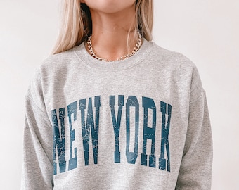 May include: Gray sweatshirt with a navy blue "NEW YORK" graphic printed on the front.