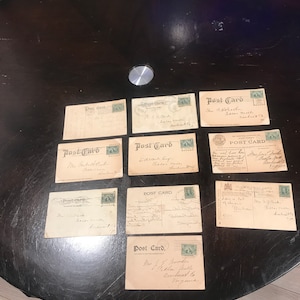 Może przedstawiać: Dziewięć pocztówek vintage z nadrukowanym tekstem "Post Card". Pocztowki są w różnych kolorach i mają różne wzory. Niektóre pocztówki mają znaczki.