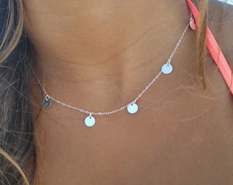 May include: A silver chain necklace with four small, round silver charms hanging from it.