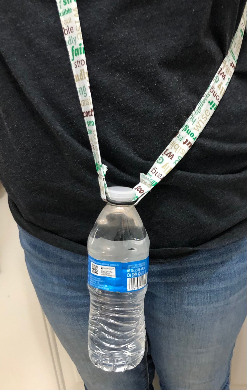 May include: A clear plastic water bottle with a blue label that says "ONTOS CH-ME 50 CA CRV 10" is attached to a white lanyard with green and brown text. The lanyard is worn around a person's neck.