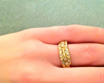 Puede incluir: Un anillo de oro con tres bandas engastadas con pequeños diamantes.