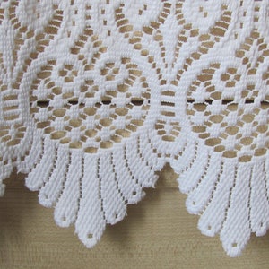 May include: White lace trim with a scalloped edge. The lace has a delicate floral pattern.
