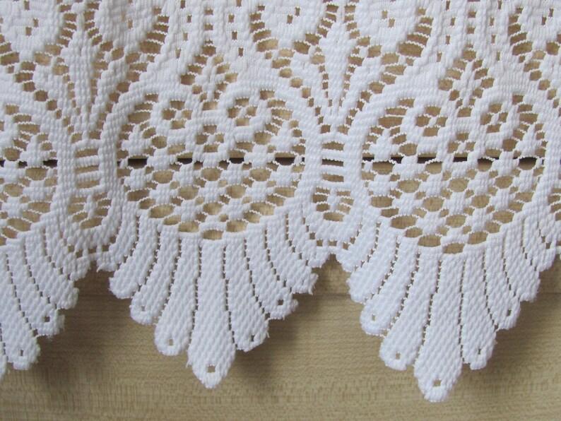 May include: White lace trim with a scalloped edge. The lace has a delicate floral pattern.