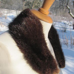 Puede incluir: Un cuello de piel marr&oacute;n sobre un maniqu&iacute; blanco. El cuello est&aacute; hecho de piel suave y esponjosa y es perfecto para a&ntilde;adir un toque de lujo a cualquier atuendo.