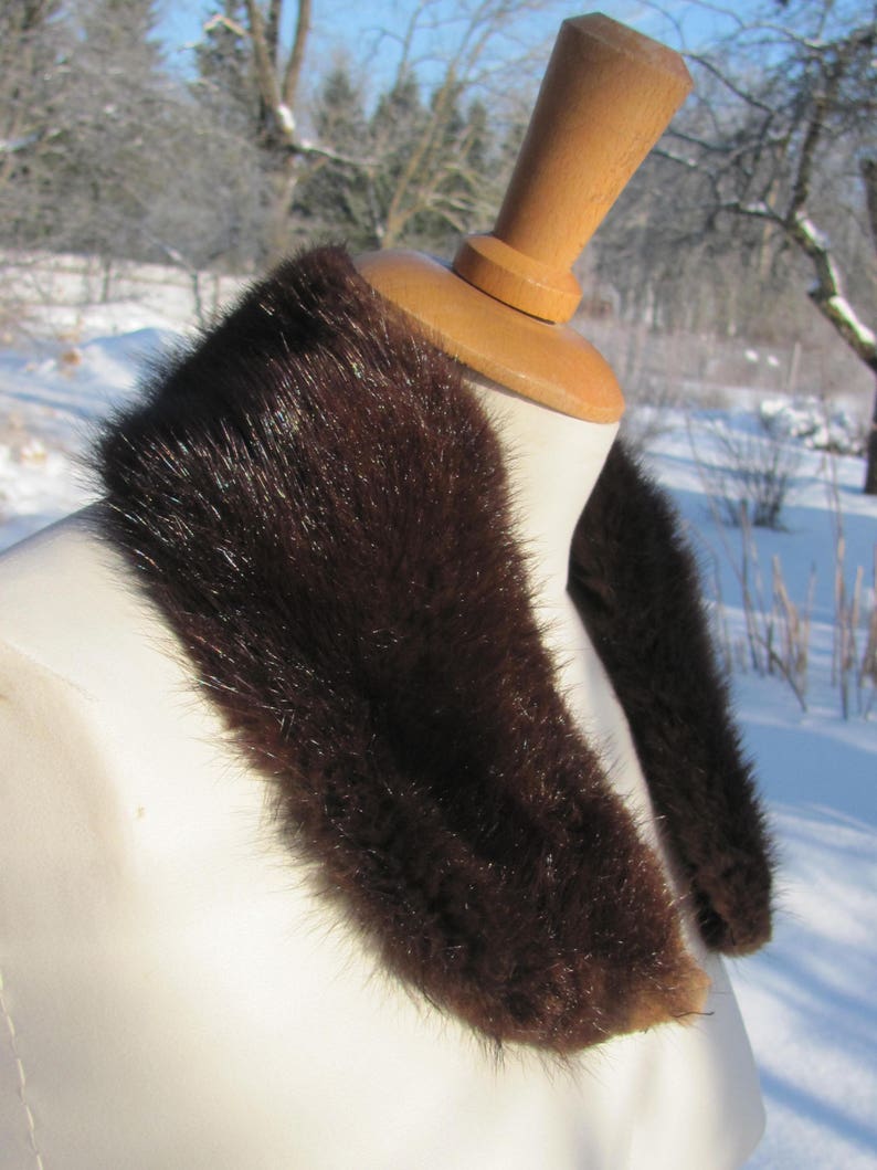 Puede incluir: Un cuello de piel marr&oacute;n sobre un maniqu&iacute; blanco. El cuello est&aacute; hecho de piel suave y esponjosa y es perfecto para a&ntilde;adir un toque de lujo a cualquier atuendo.